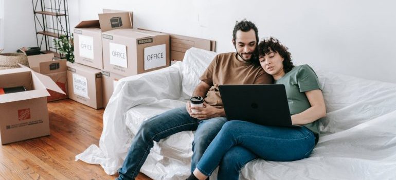 Couple Sitting On A Couch Browsing On Computer