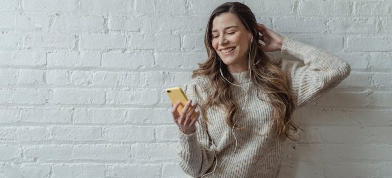 Positive young woman talking on smartphone via earphones