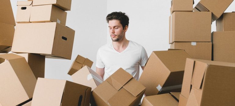 Man between stacks of cardboard boxes at home