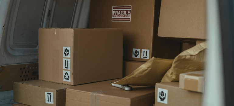 Close-up of cardboard boxes inside a delivery van, with fragile labels and moving icons — trusted movers Huntington Beach in action.