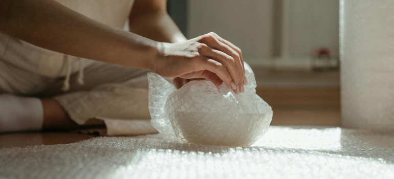 Person holding white plastic bag showing careful handling, highlighting the Benefits of white glove movers in Los Angeles for delicate items.