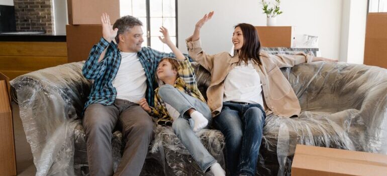 Happy Family Sitting on the Couch Covered with Plastic after moving and following tips for a smooth move in Beverly Hills
