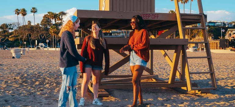 A group of woman are standing on the beach discussing about moving to Santa Monica in 2025.