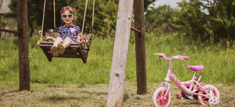 Child on Swing with Pink Bike Outdoors