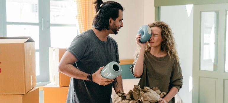 A couple is playing with a ceramic vase in their new apartment.