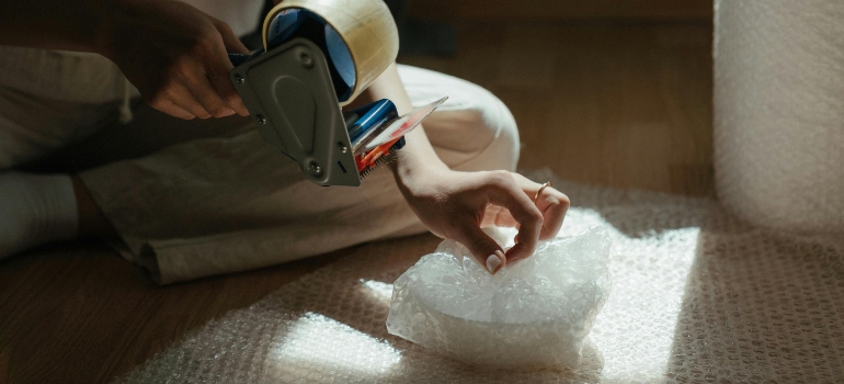 Person carefully wrapping a very fragile item with bubble wrap for safe moving.