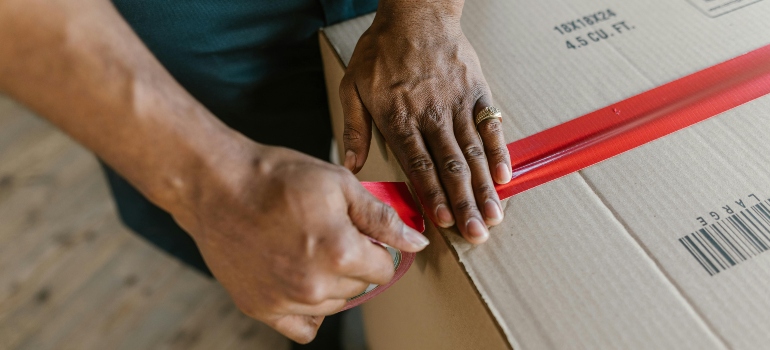 Professional mover carefully packing a cardboard box to protect items during a move in Woodland Hills.