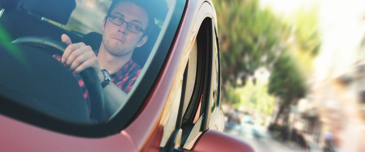 A person holding the steering wheel while driving, with blurred scenery outside the car, capturing the feeling of travel and highlighting what to know before moving from Agoura Hills to Long Beach.