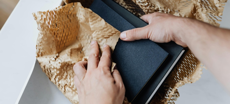 Anonymous man wrapping and preparing notebooks for moving, showing organized packing for leaving West Covina for Costa Mesa.