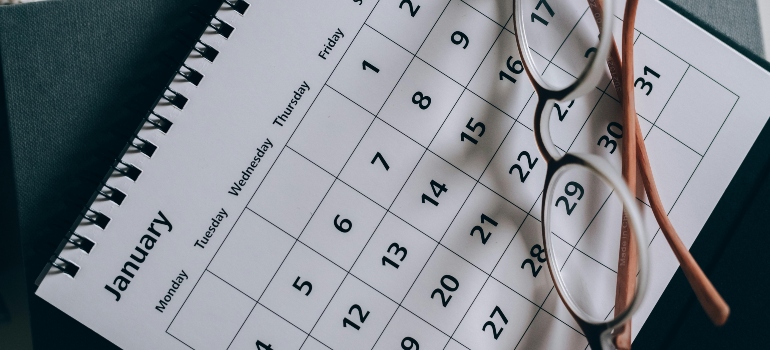 Brown-framed eyeglasses placed on a calendar as a reminder that planning ahead shows why using storage during a Los Angeles move makes everything easier.