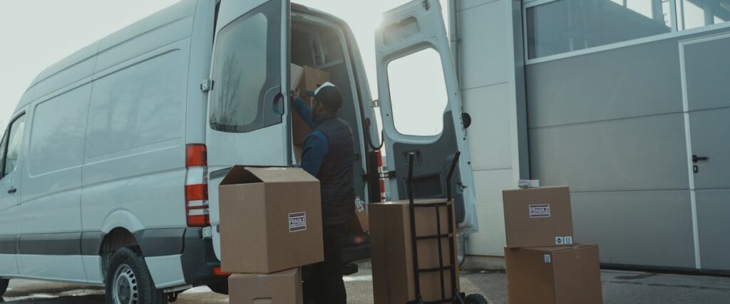 Delivery worker loading boxes into a white van on a busy loading dock, illustrating warehouse moving LA operations.