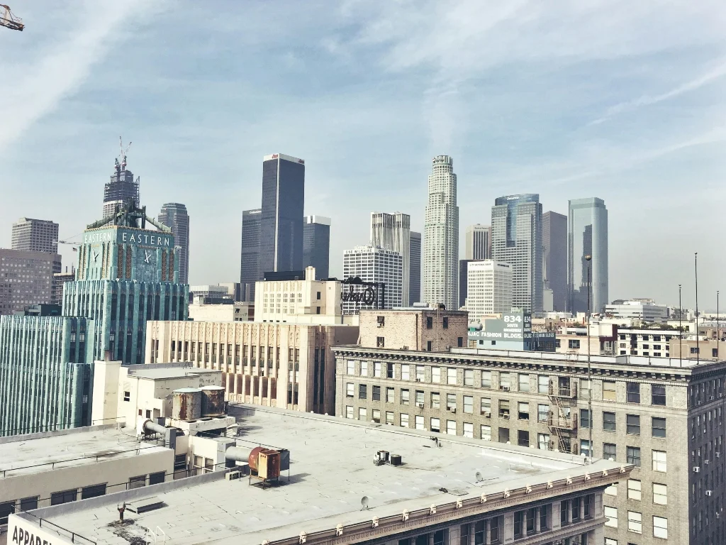 View of downtown Los Angeles showing a mix of historic architecture and modern skyscrapers on a hazy day.