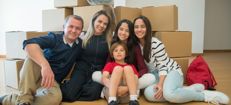 A family is taking a picture in their new home, in front of the boxes.