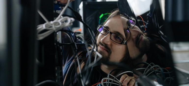 Employee Working Through the Tangle of Cables Behind the Computer