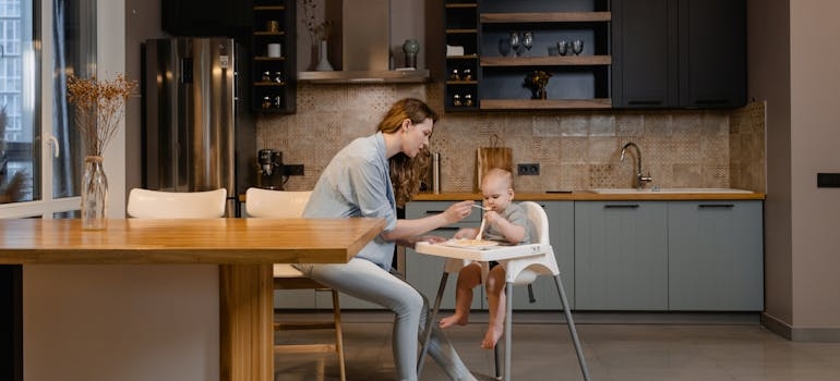 Parent feeding a baby in a modern kitchen, showing daily life after a household move.