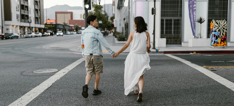 Couple holding hands while crossing a Pasadena street, joyfully ignoring the red light vibes.