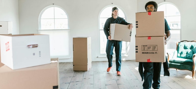 Two Culver City movers carrying boxes in a bright room during a professional moving service.