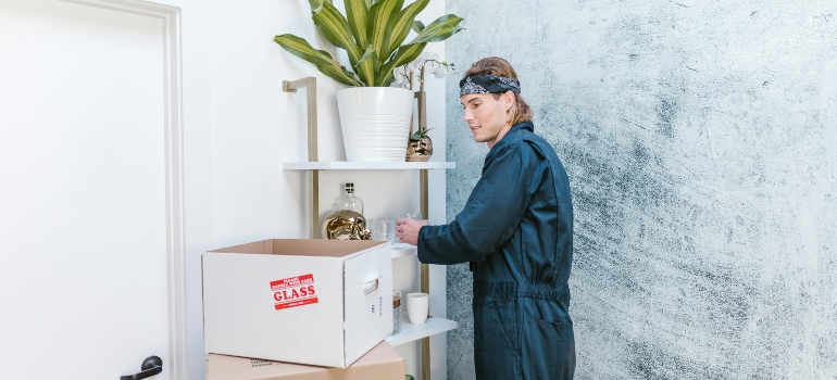 Professional mover packing delicate glassware near a 'Fragile Glass' labeled box, showcasing Whittier CA movers' precision.