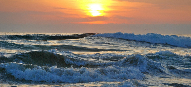Waves rolling under a golden sunset, as if the sea is humming to itself.