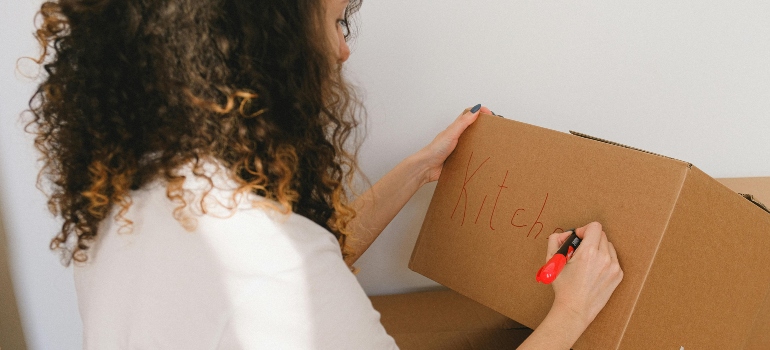 Woman marking moving boxes while planning her new space in Pasadena to support downsizing and organized unpacking